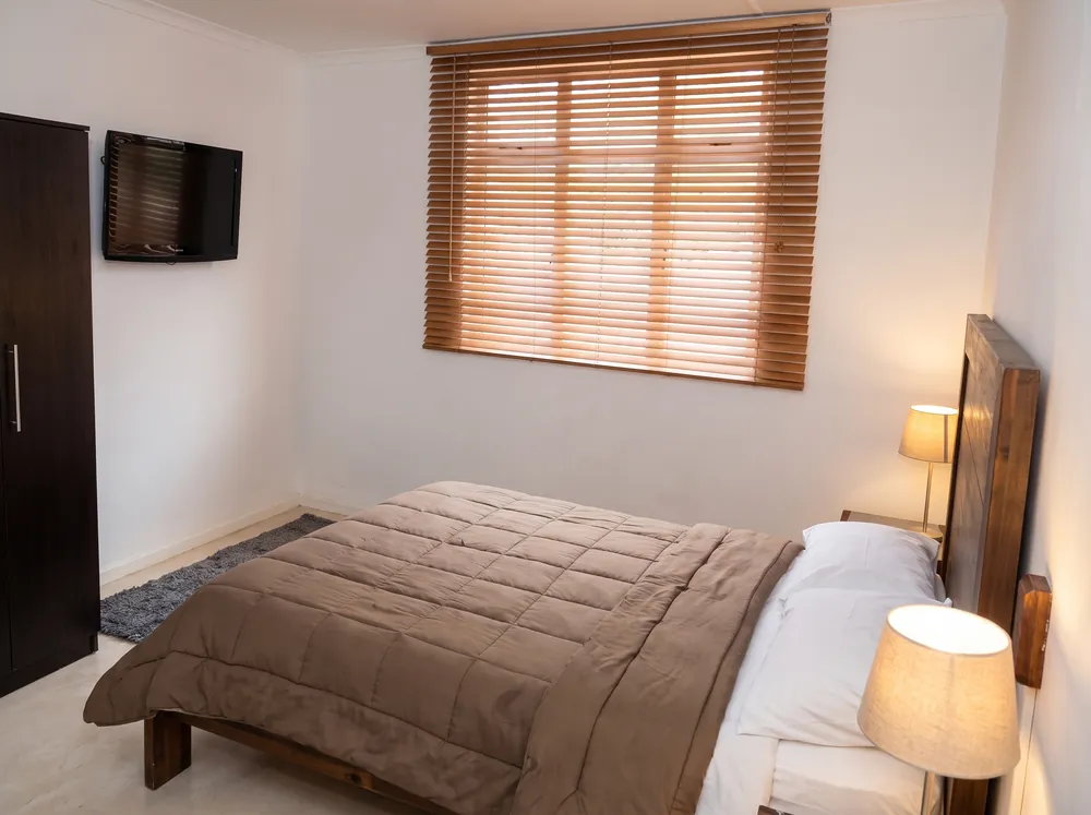 Habitación con persiana y cama doble